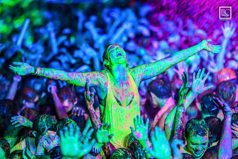 girl covered in paint with arms out wide